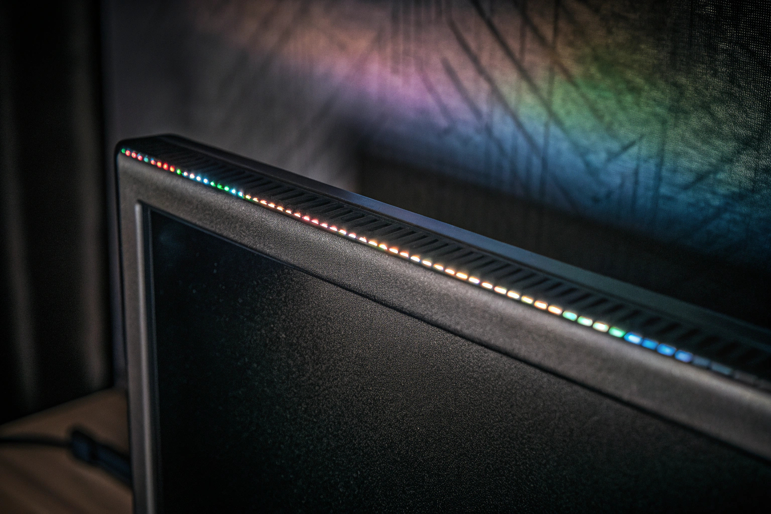 Detailaufnahme einer RGB-LED-Lightbar, die hinter einem Monitor platziert ist und das Setup mit bunten Farben beleuchtet. RGB-LED-Lightbar Gaming-Beleuchtung