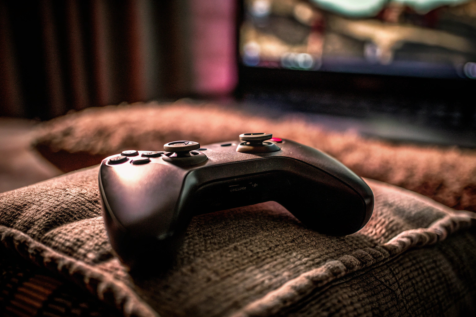 Detailaufnahme eines Videospiel-Controllers mit einem Laptop im Hintergrund, bereit für eine Gaming-Session. Videospiel-Controller mit Laptop