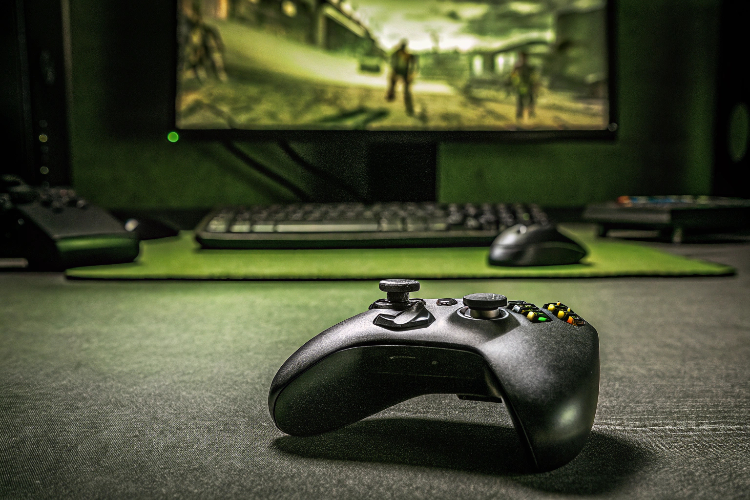 Ein Gamer, der mit einem Gamepad ein PC-Spiel spielt, umgeben von seiner Gaming-Ausrüstung. PC-Gamer mit Gamepad