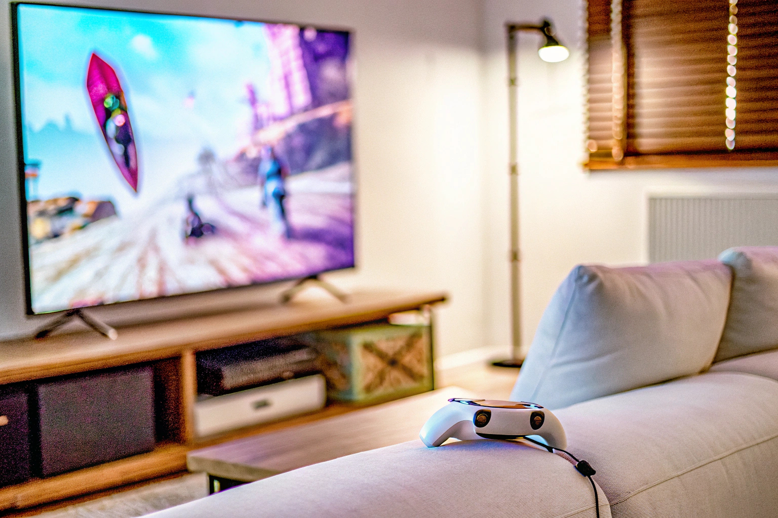 Ein Gamer, der mit einem Headset und einem Controller auf einem Sofa sitzt und auf einem großen Bildschirm spielt. Gamer beim Cloud Gaming