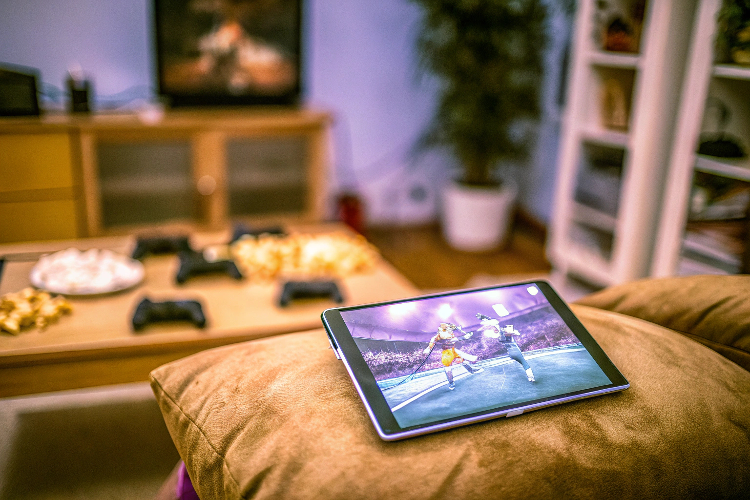 Ein Kind, das mit einem digitalen Gerät ein Multiplayer-Spiel spielt. Im Hintergrund sitzen Freunde, die ebenfalls spielen. Kind spielt digitales Multiplayer-Spiel