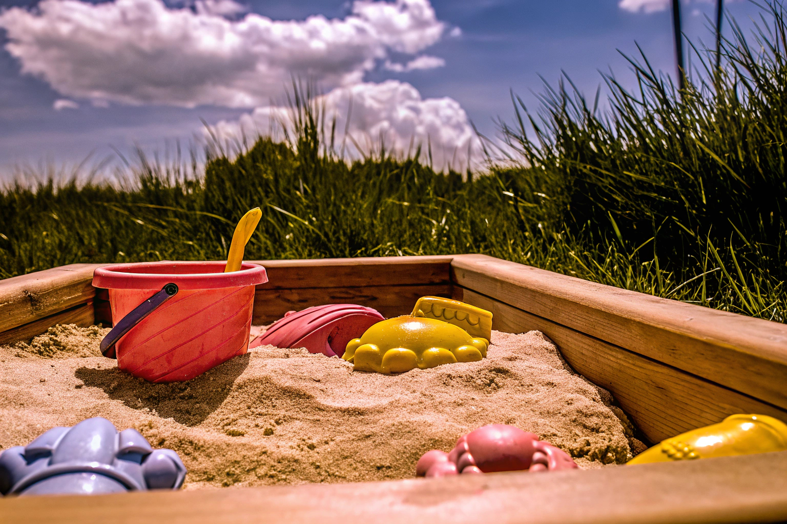 Ein Kind spielt mit einem Sandkasten und verschiedenen Sandspielzeugen. Kind spielt mit Sandkasten und Sandspielzeugen