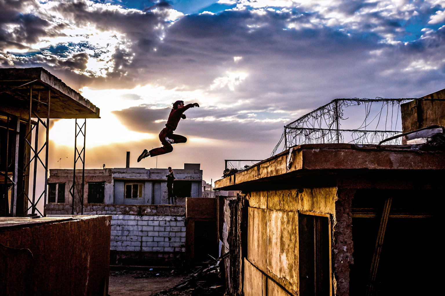Ein Spieler in Dying Light 2 springt über die Dächer einer verlassenen Stadt bei Sonnenuntergang. Dying Light 2 Parkour