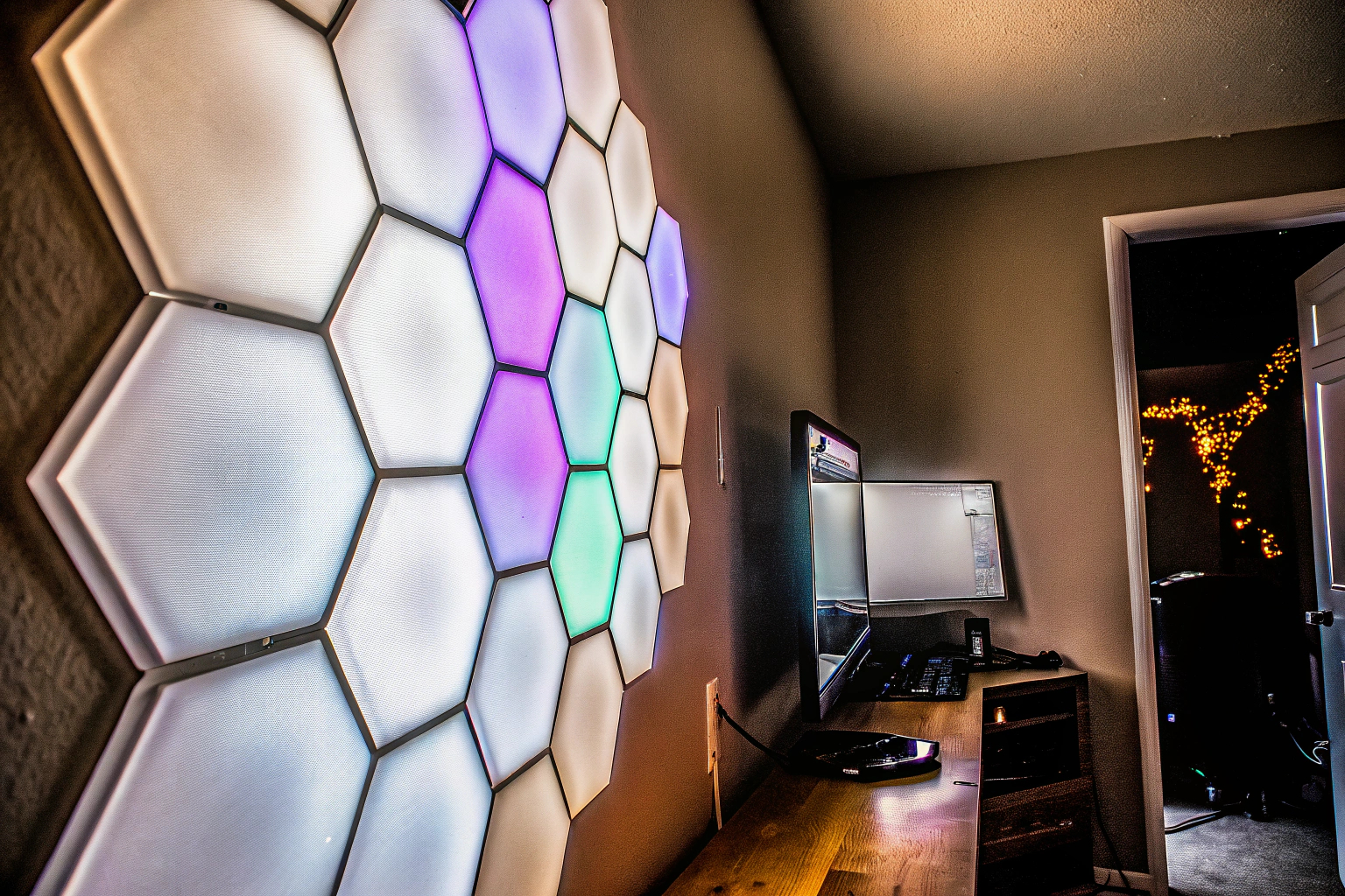 Eine Gaming-Wand mit LED-Sechseck-Wandleuchten, die in verschiedenen Farben leuchten. LED-Sechseck-Wandleuchten im Gaming-Zimmer