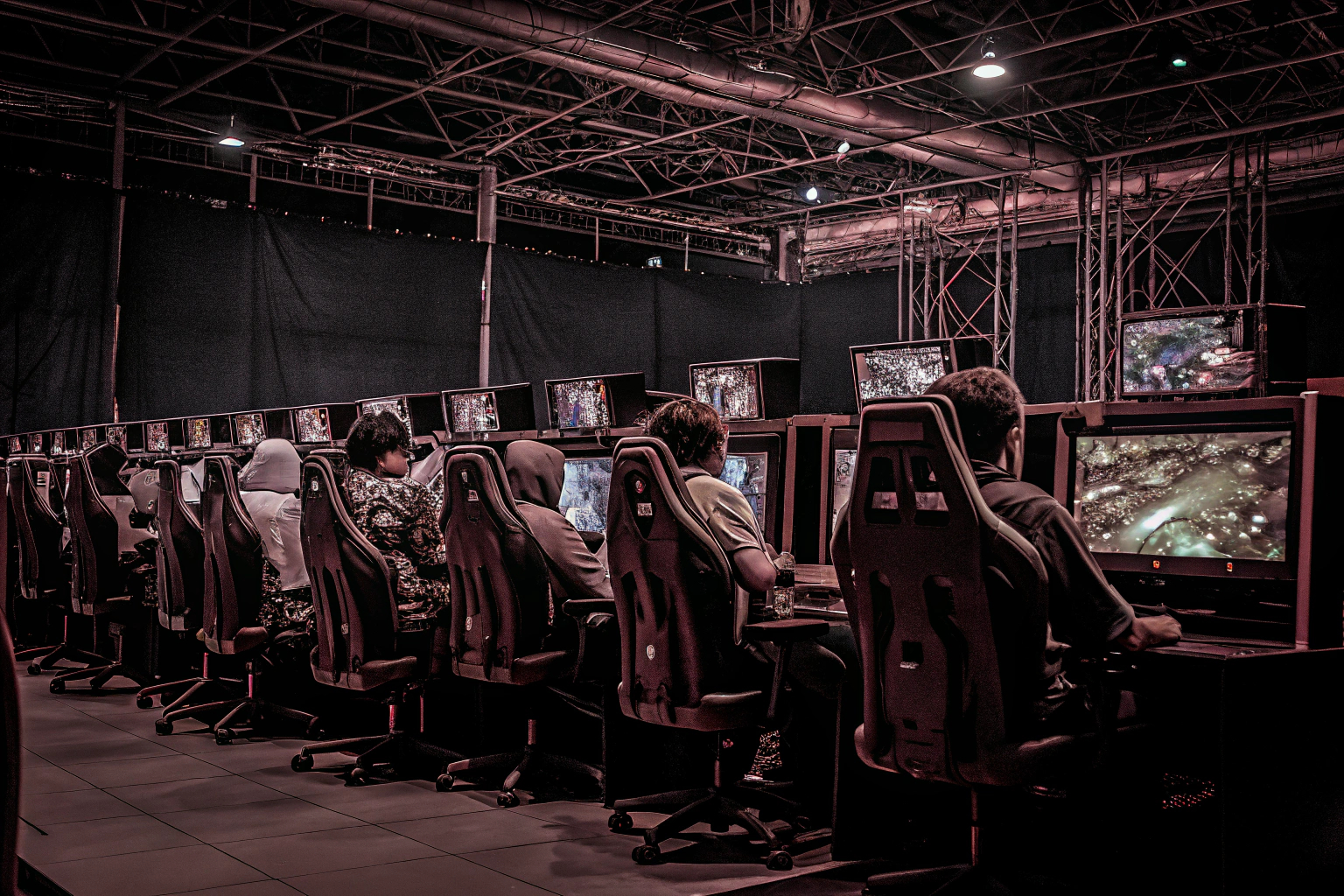 Eine Gruppe von E-Sport-Spielern bei einem großen Turnier, ihre Bildschirme leuchten in verschiedenen Farben. E-Sport-Turnier