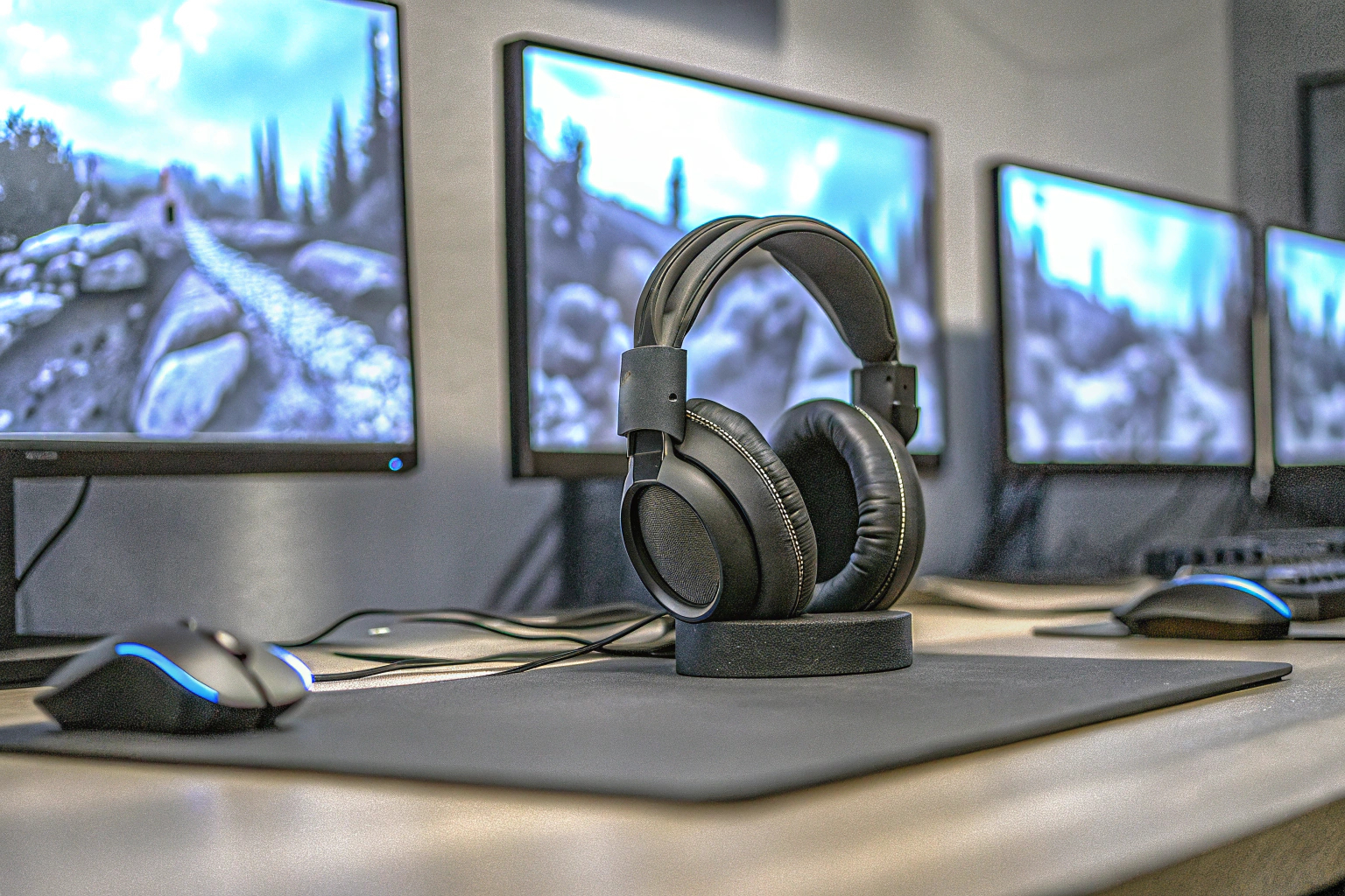 Gaming-Setup mit mehreren Monitoren und einem hochwertigen Gaming-Headset auf einem Schreibtisch. Gaming-Setup mit Surround Sound Headset