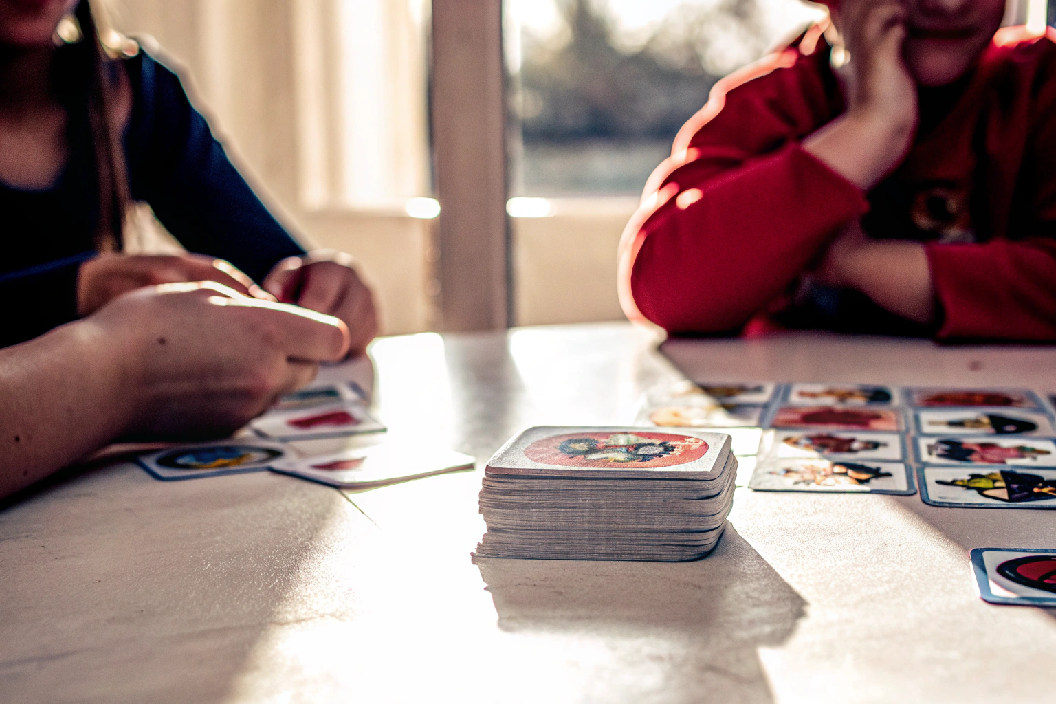 Kinder spielen das Dobble Kids Kartenspiel, umgeben von Karten mit Tiermotiven. Dobble Kids Kartenspiel mit Tiermotiven