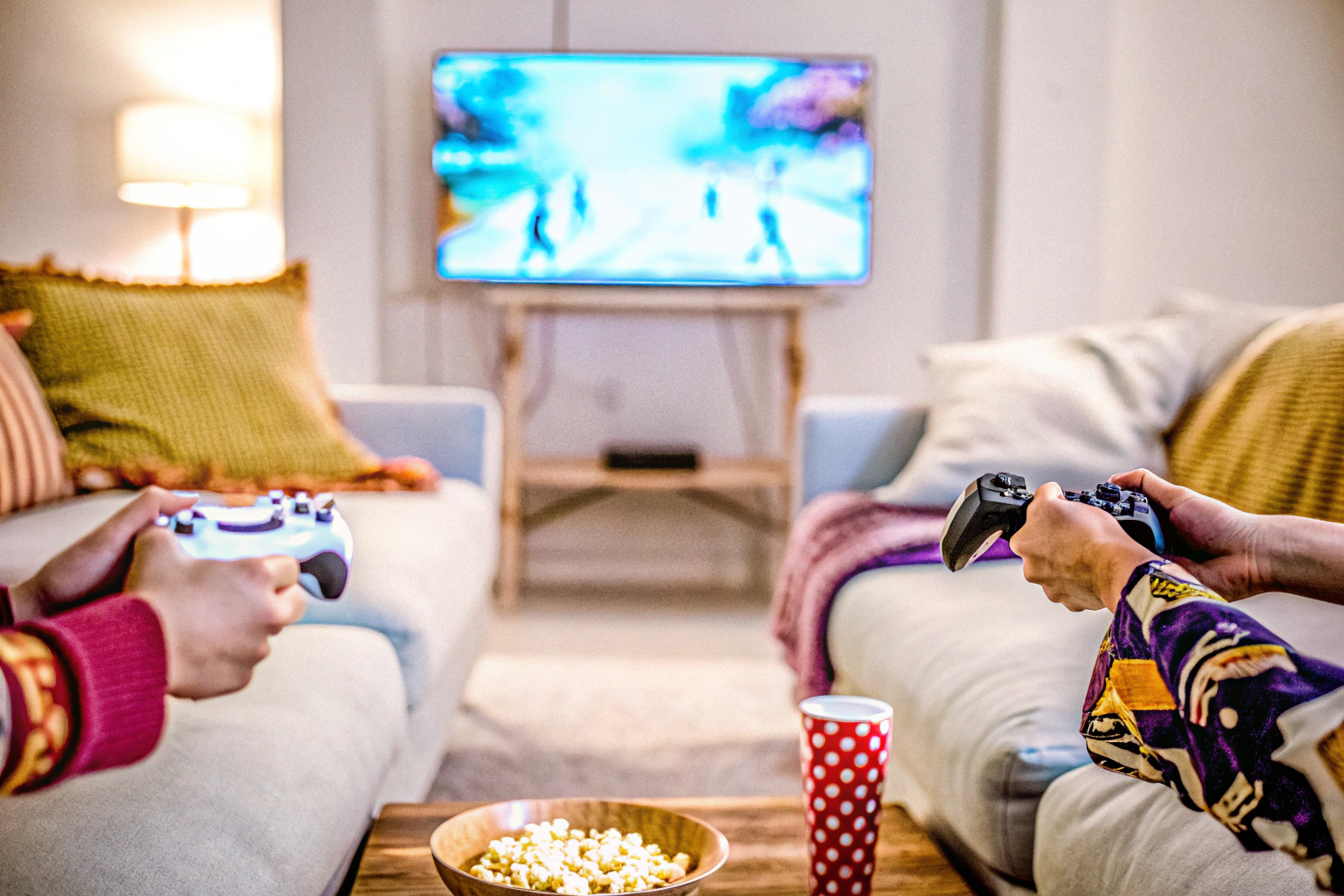 Zwei Spieler, die auf einer Couch sitzen und ein Videospiel im Split-Screen-Modus spielen. Zwei Spieler im Split-Screen-Videospiel